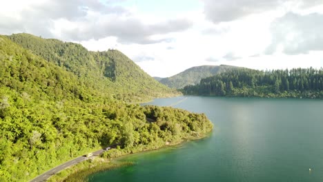 Blue-Lake,-palm-forest-road-and-tourist-on-paddle-bord-4k-drone-shot-in-New-Zealand