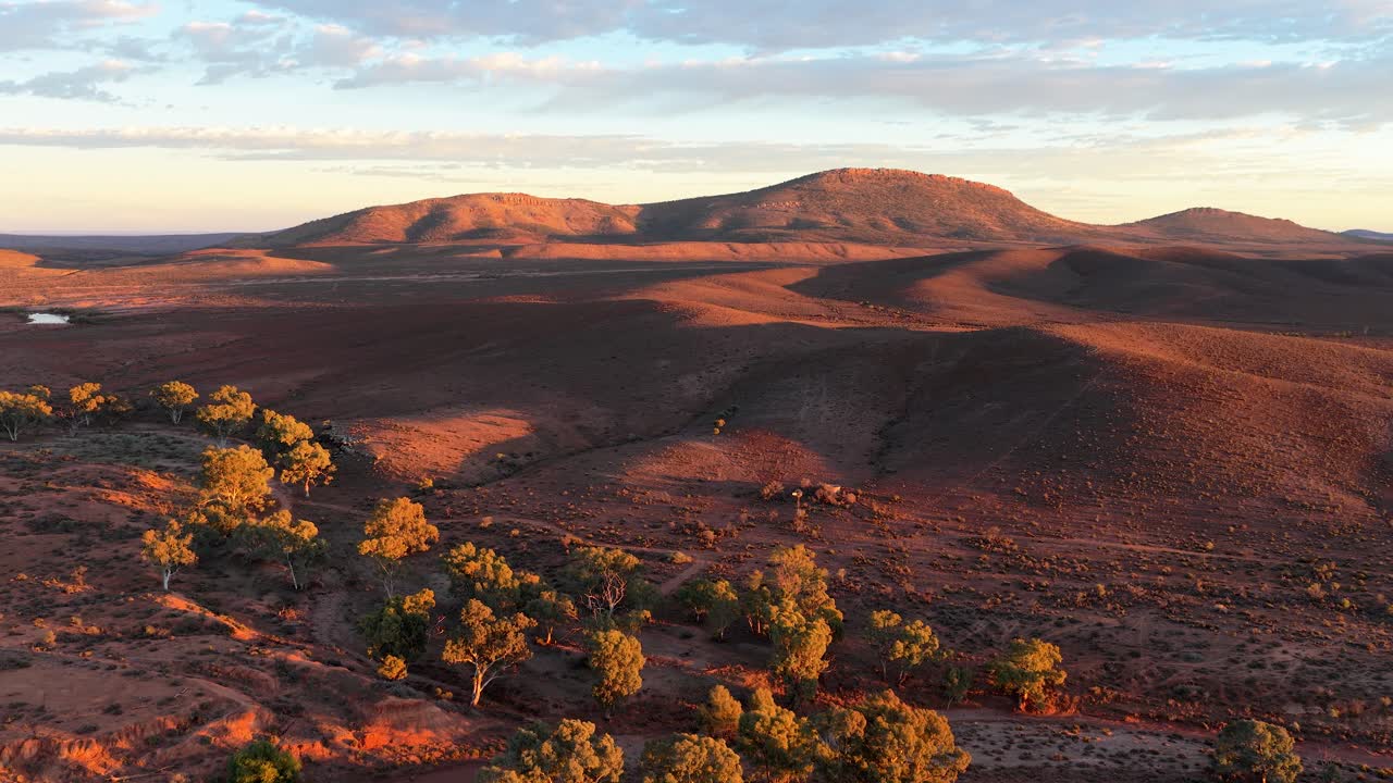Drone shot of arid outback landscape with winding dry creek bed and sunlit hills, Flinders Ranges, South Australia