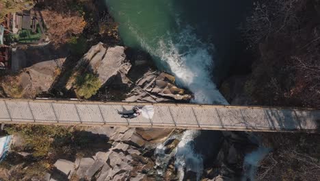 Frischvermählte.-Braut-Und-Bräutigam-Liegen-Auf-Einer-Brücke-über-Einem-Gebirgsfluss.-Luftaufnahme