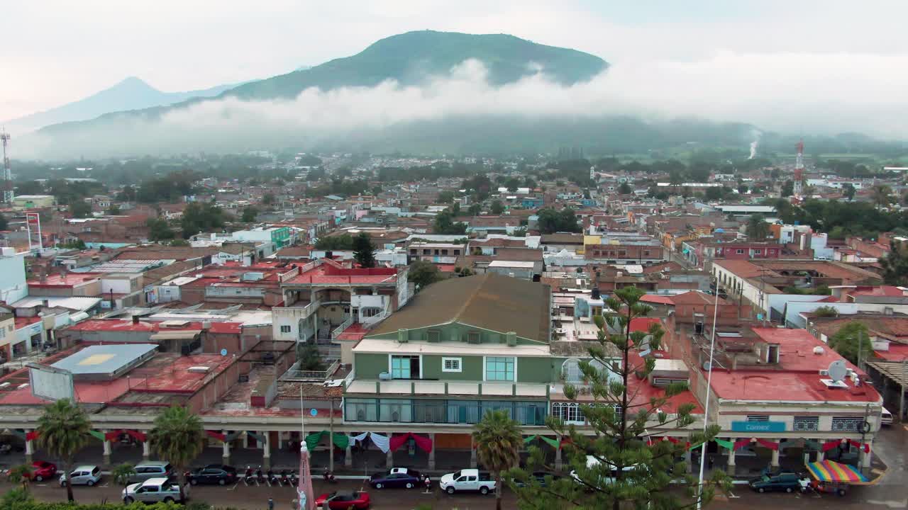 Aerial: cityscape and mountain top over the city during the day in Tuxpan, Jalisco, Mexico, push in drone shot