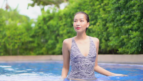 sophisticated asian woman walking sensual in swimming pool slomo