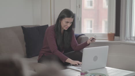 Junge-Attraktive-Frau-Gibt-Kreditkartendaten-In-Den-Laptop-Ein,-Um-Online-Einzukaufen,-Und-Feiert,-Wenn-Sie-Mit-Der-Faustpumpe-Fertig-Ist---Unbenotet