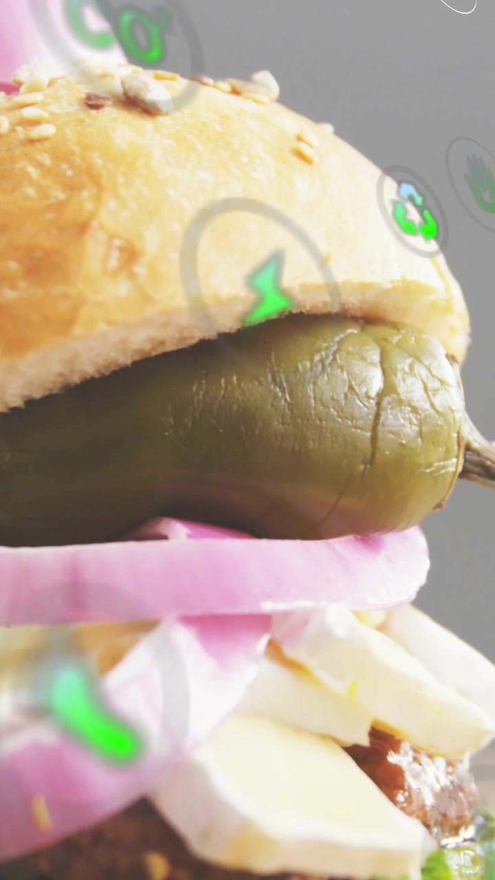Video verticale: Telecamera in pausa che mostra un panino ai semi con spiedino e pepe, con icone fluttuanti che mostrano cibo.