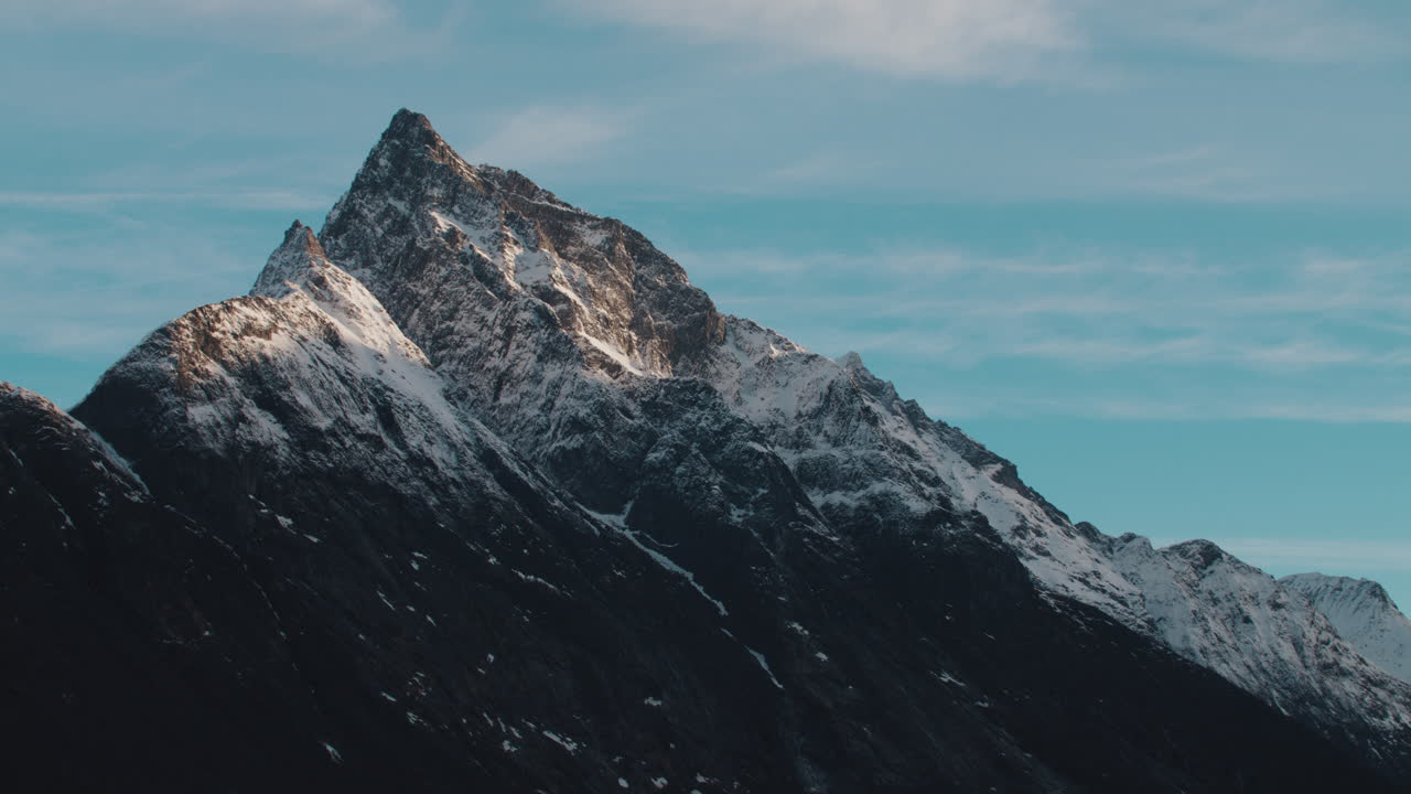 Naturskønt billede af en bjergtop med sne, der dækker bjergene, og solen skinner klart på den en kold vinterdag i Norge.
