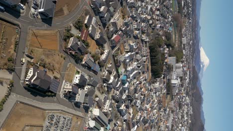 Slow-cinematic-vertical-tilt-up-over-suburban-Japanese-city-and-Mount-Fuji