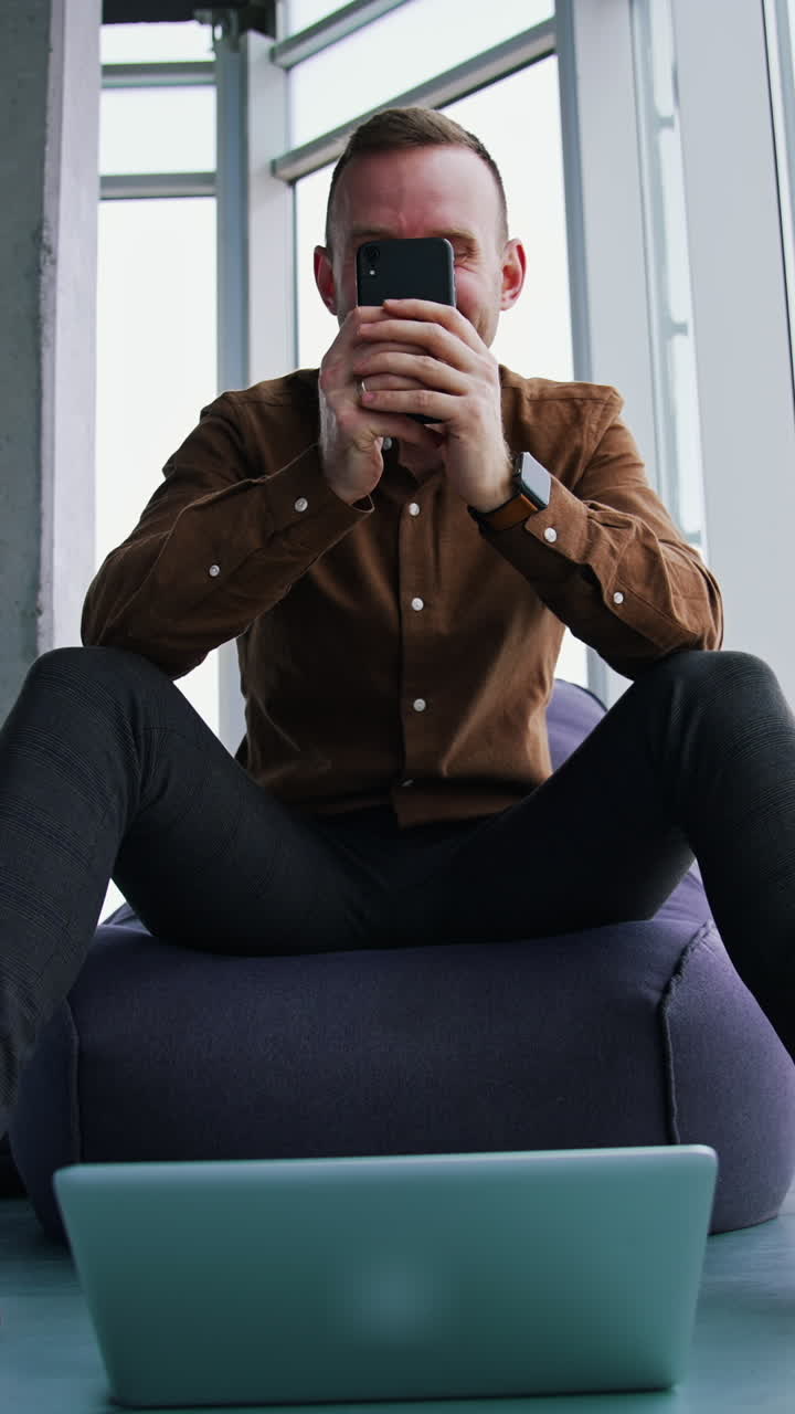 Handsome businessman writing notes from smartphone at modern office Vertical video