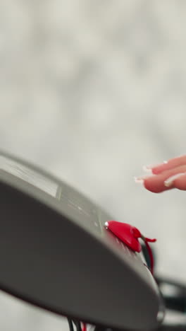 woman presses start key on treadmill control panel at home closeup. lady setups gym machine speed for exercising indoors. sports equipment technology