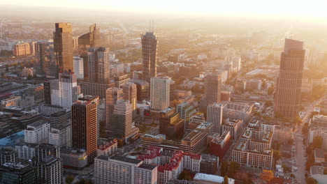 Slide-and-pan-aerial-panoramic-footage-of-modern-downtown-buildings-in-morning-sun-glow.-Warsaw,-Poland