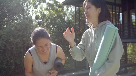 Glückliche-Asiatische-Freundinnen-Mit-Trainingsmatten-Und-Wasserflasche-Lachen-Auf-Der-Terrasse,-Zeitlupe