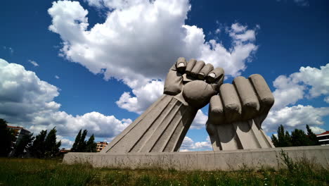 monumental concrete fist sculpture against a cloudy sky