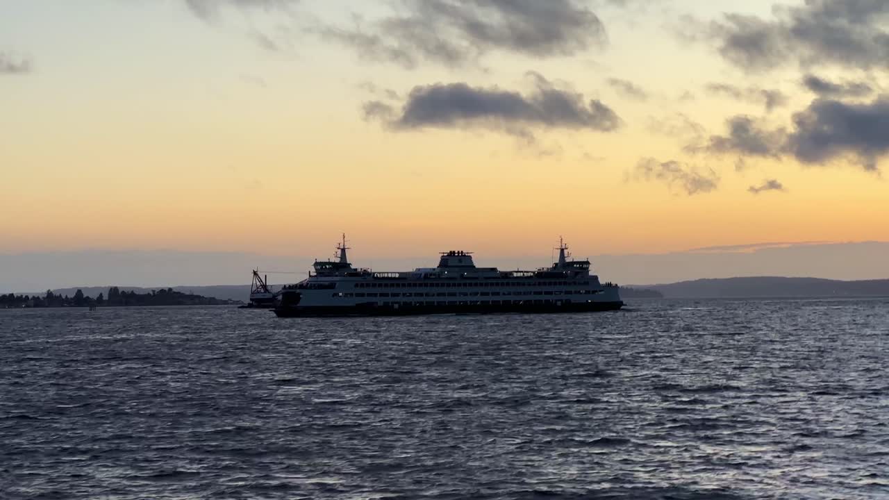 Handheld, breedbeeldopname vanaf een bewegende boot van de Washington State Ferry op Elliott Bay bij zonsondergang in Seattle. 4K