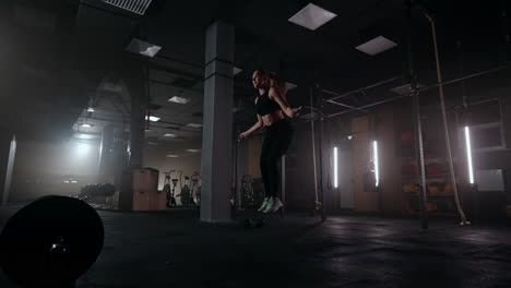 young slender woman is training alone in gym skipping rope for warming body before hard workout