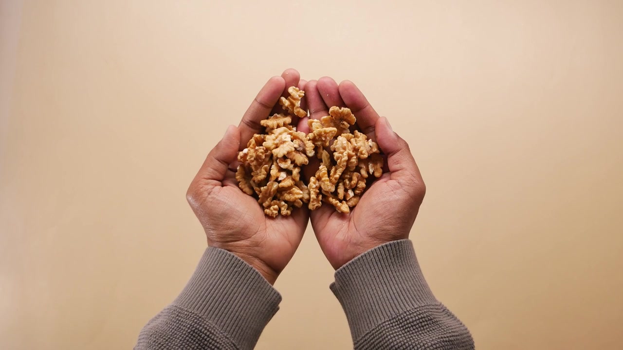 Person Holding a Handful of Shelled Walnuts