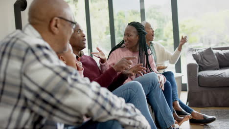 Excited-african-american-parents,-son,-daughter-and-grandparents-watching-sport-on-tv,-slow-motion