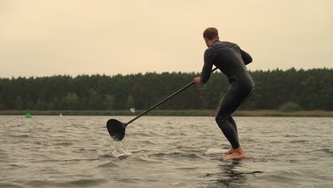 hydro sup foil athlete on board standing up and start paddle in slow motion close up