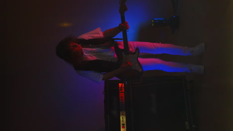 Vertical-video-rock-guitarist-playing-guitar-in-the-Studio-in-the-light-of-spotlights-and-smoke