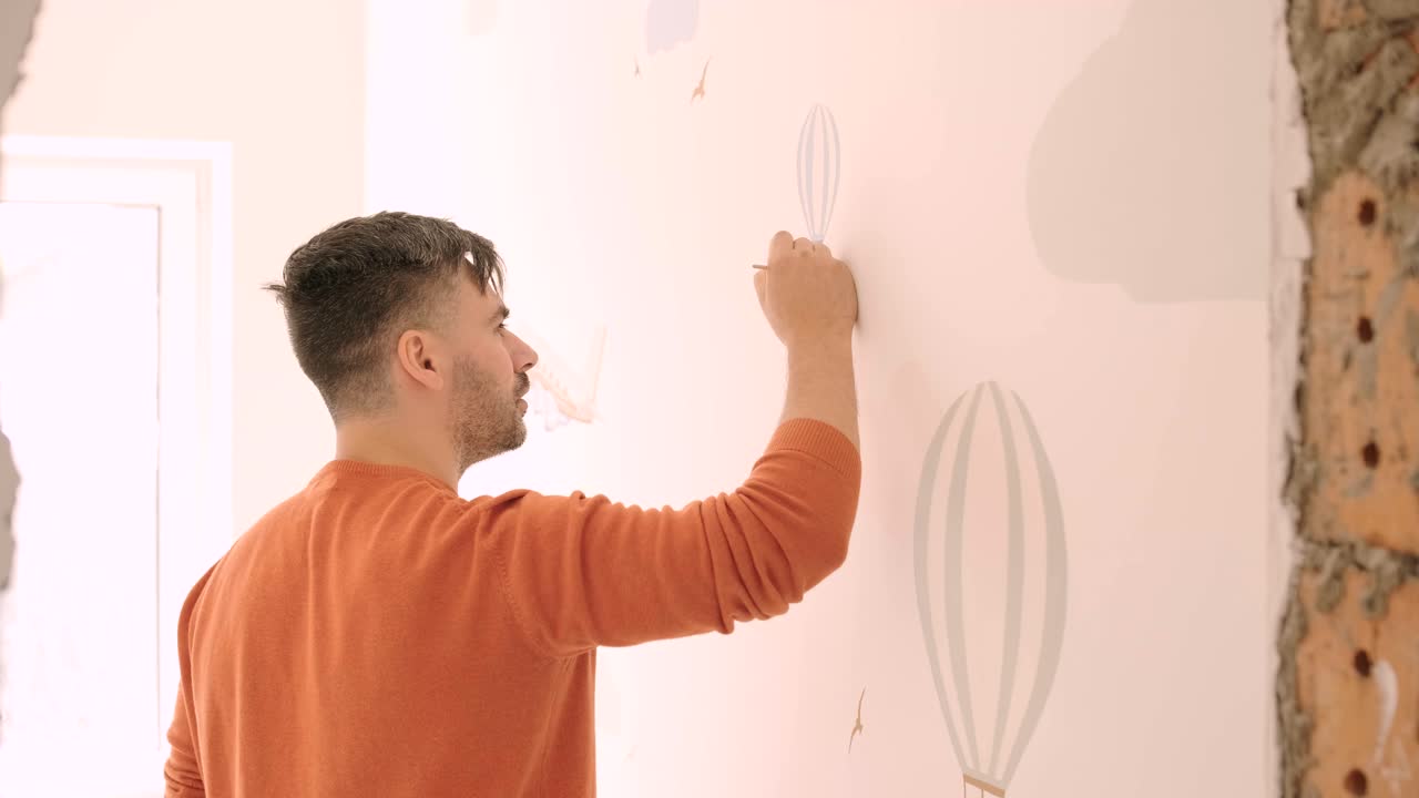 el artista está decorando las paredes con dibujos en la habitación de los niños. pintura de arte de las paredes en la casa nueva. trabajos de reparación.