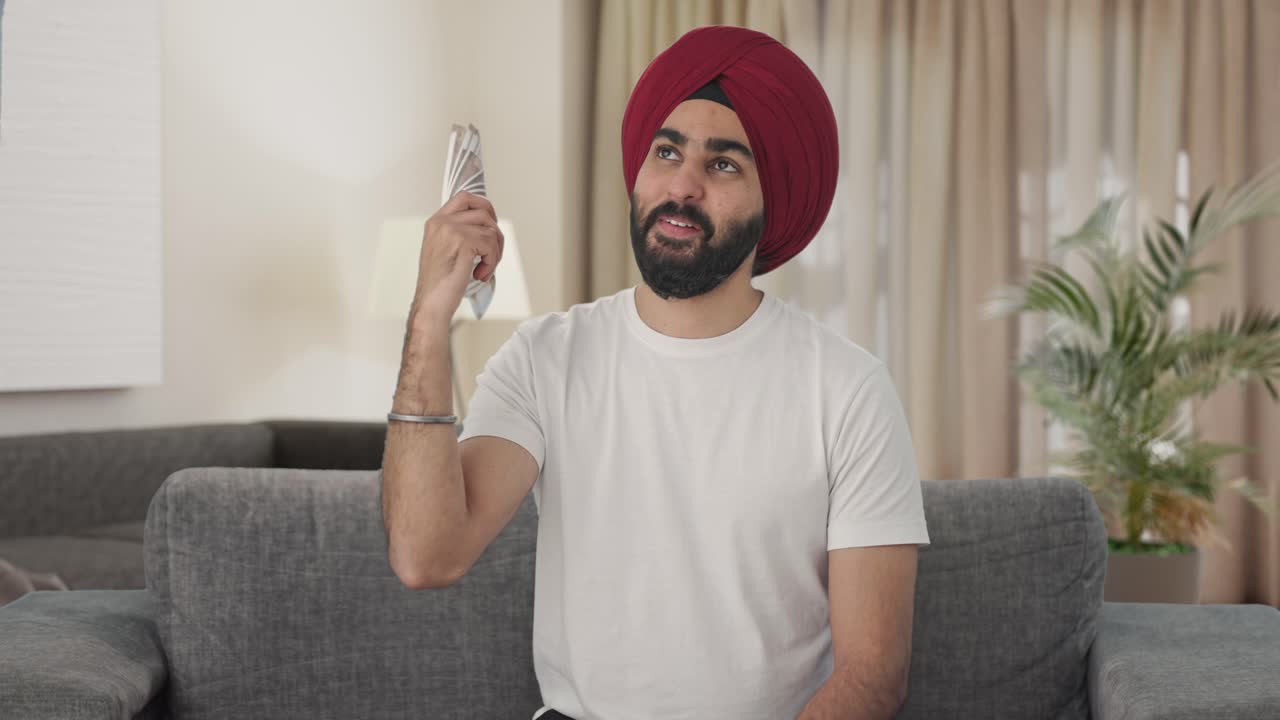 Felice uomo Sikh indiano che si sventola con i soldi.