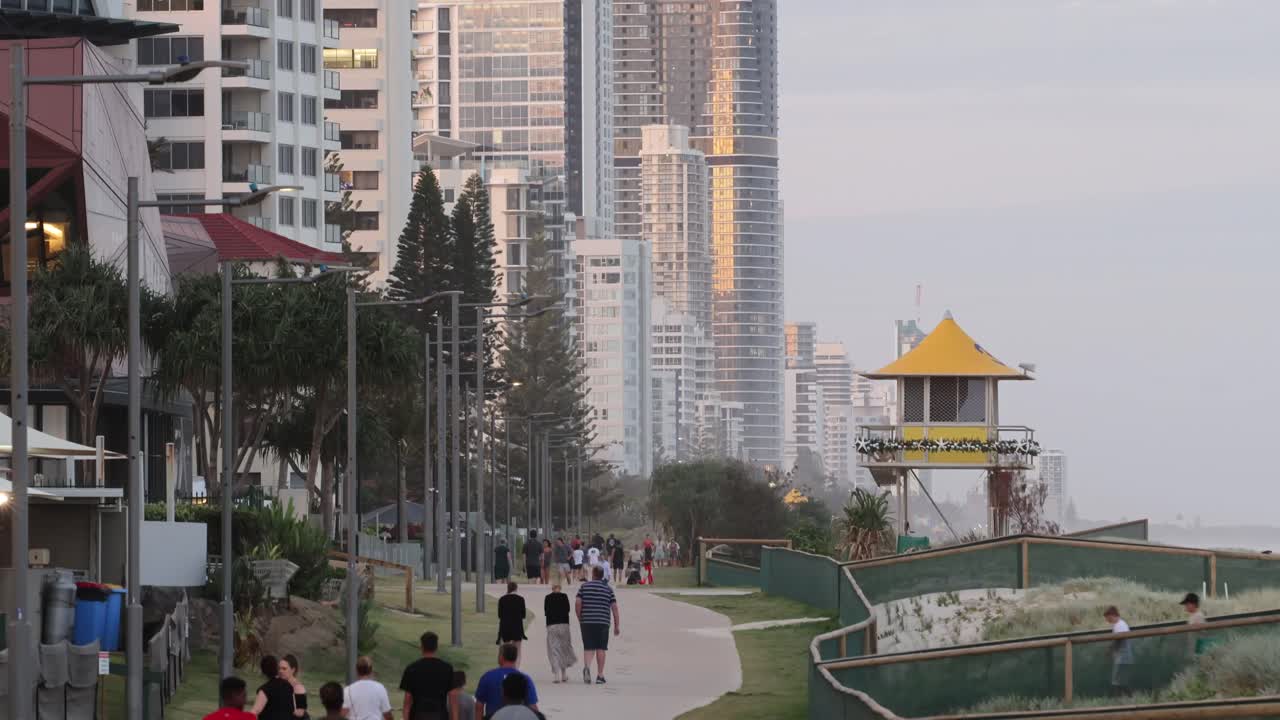 Persone che camminano in un parco con grattacieli al tramonto