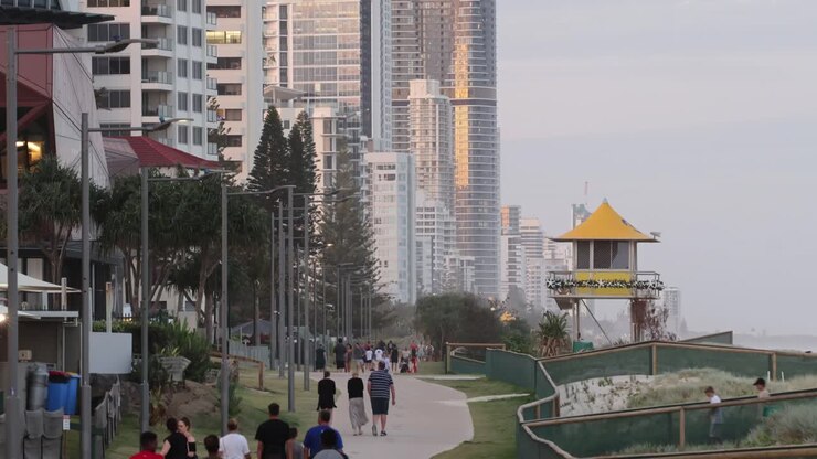 Persone che camminano in un parco con grattacieli al tramonto