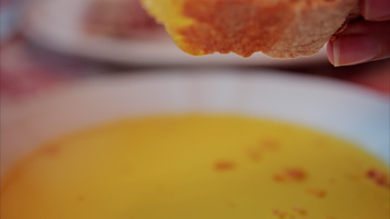 Close up of a woman dipping a piece of bread in an oil plate