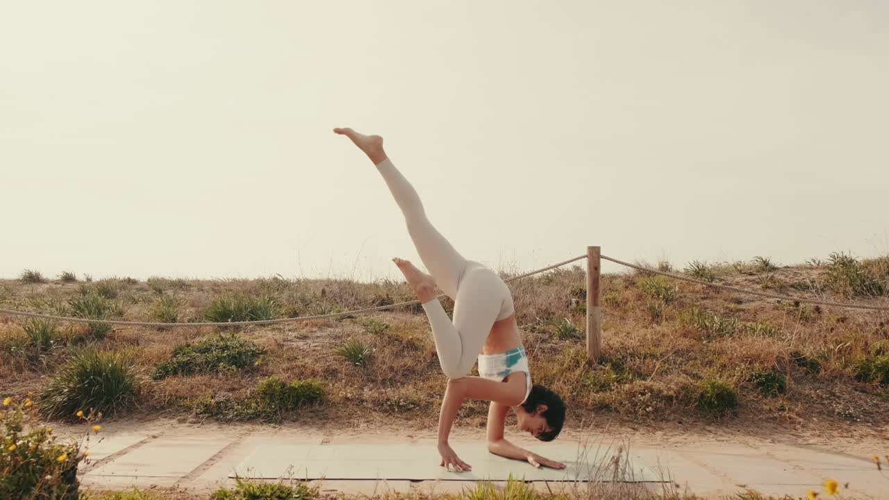 Frau praktiziert Yoga-Handstand auf einer Matte im Freien