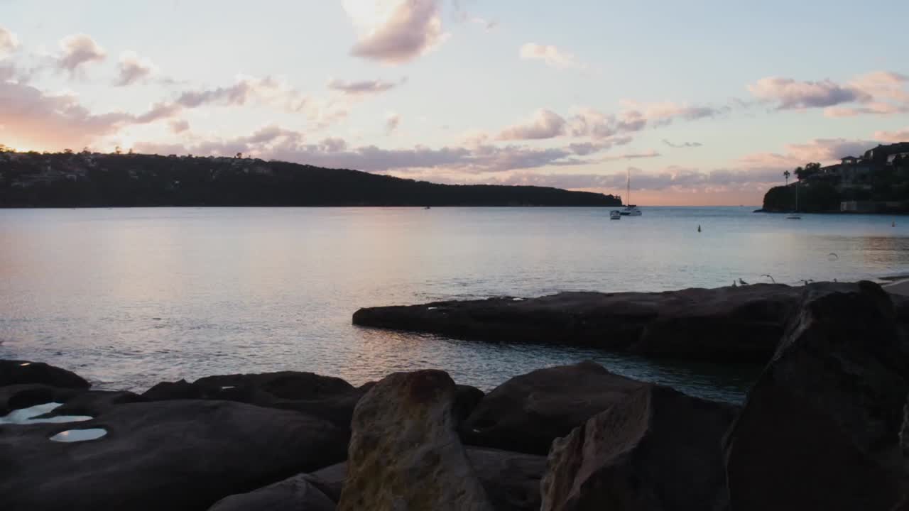 Timelapse af Sydney Bugt ved daggry med både og skyer i bevægelse, alt skifter fra mørke til lys, når dagen gryr