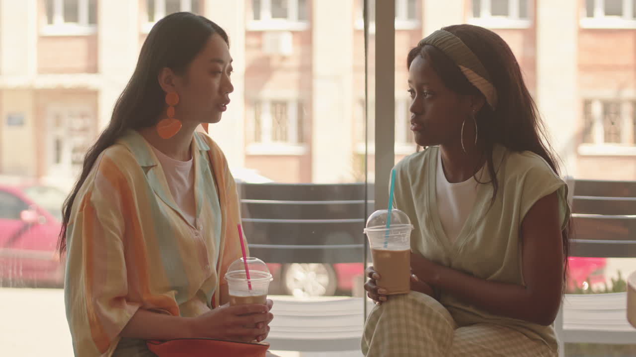 Girlfriends Chatting by Window at Cafe