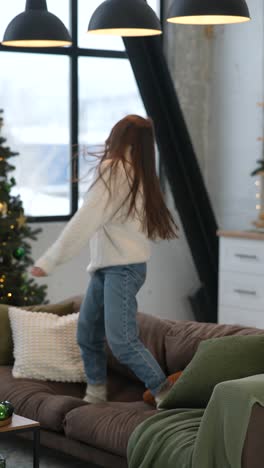 woman jumping on sofa with christmas gifts