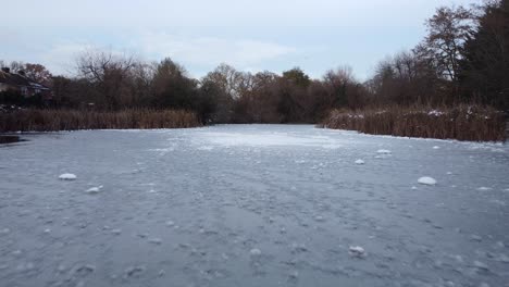 Drone-flying-over-frozen-lake-in-natural-countryside-of-England-in-winter