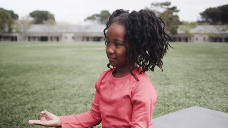 young girl meditating on grass at school, enjoying peaceful outdoor moment, copy space