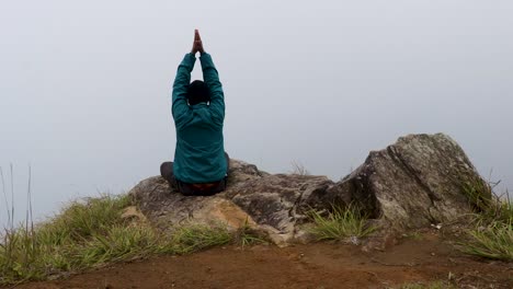 man meditating at mountain rock with white mist background from flat angle