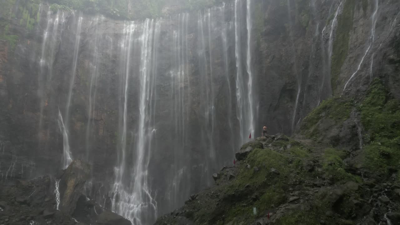 turista masculino disfruta de la dramática cascada de niebla de tumpak sewu en java, en el