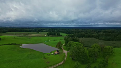 scenic latvian landscape over green fields and trees with an aerial drone shot of a small lodge below