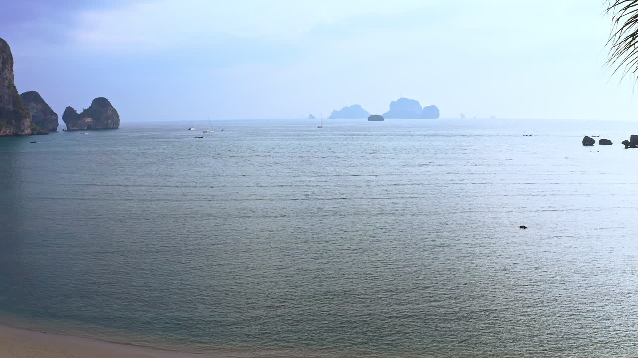 바위 절벽과 선박이 있는 태국의 오션 베이 해변에 손바닥 두 개