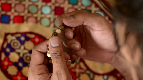 man's hand with wooden prayer beads, goes through prayer beads, blurred background. muslim prayer.