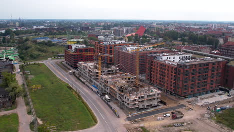 Aerial---construction-of-a-modern-residential-and-office-complex-in-the-center-of-Gdańsk---construction-site-with-cranes-and-heavy-construction-equipment---advanced-engineering-works---high-rise