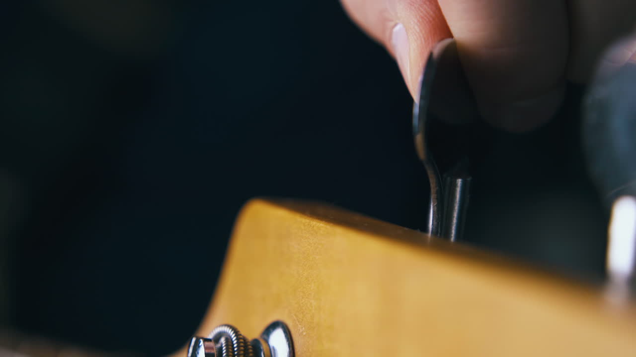 el músico afina la cuarta cuerda de bajo de metal rotando las teclas de afinación