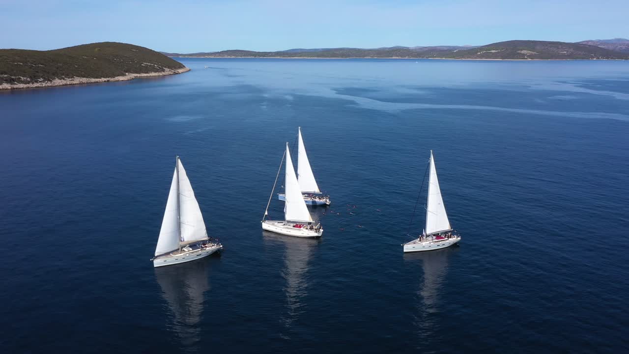 turistas nadando en un mar azul tranquilo junto a veleros blancos en hvar, croacia