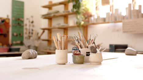 brushes, pottery tools and clay on desk in pottery studio