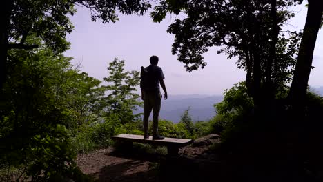 Silhouette-Of-A-Hiker-Walking-And-Stands-On-The-Bench-At-The-Top-Of-A-Mountain-In-Japan---wide-shot