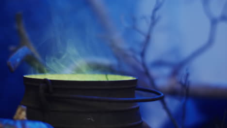 video de una olla con líquido verde y humo sobre un fondo azul