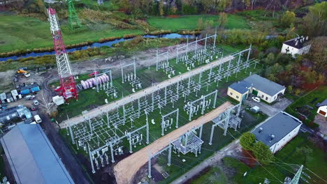 drone flying away from a power grid, at a electric station, cloudy, spring day