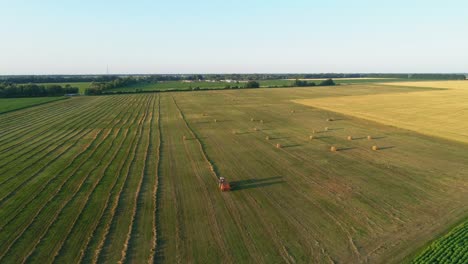 aerial view tractor baling machine making silage bales on farmland, cut wheat