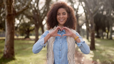 woman making heart shape with hands in park