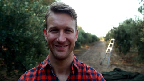 smiling man standing with arms crossed in olive farm