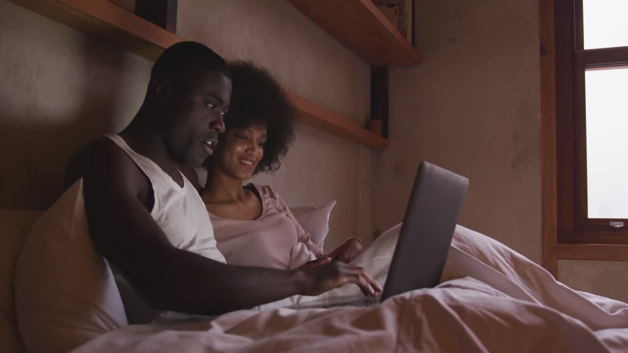 Couple using computer in bedroom at home