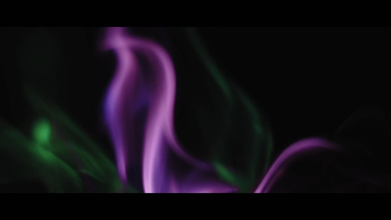 Fumo astratto verde e viola che vortica su sfondo nero