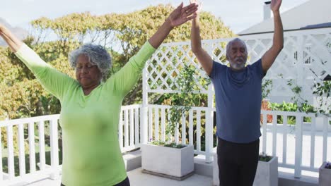 Relaxed-african-american-senior-couple-practicing-yoga-on-patio