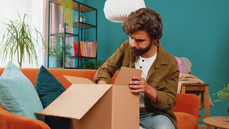 Angry-dissatisfied-shopper-middle-eastern-man-unpacking-parcel-feeling-upset-confused-wrong-delivery